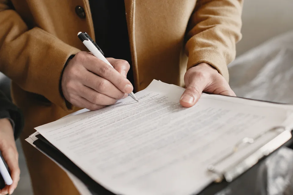 Una persona firma un contratto su una cartellina portadocumenti.